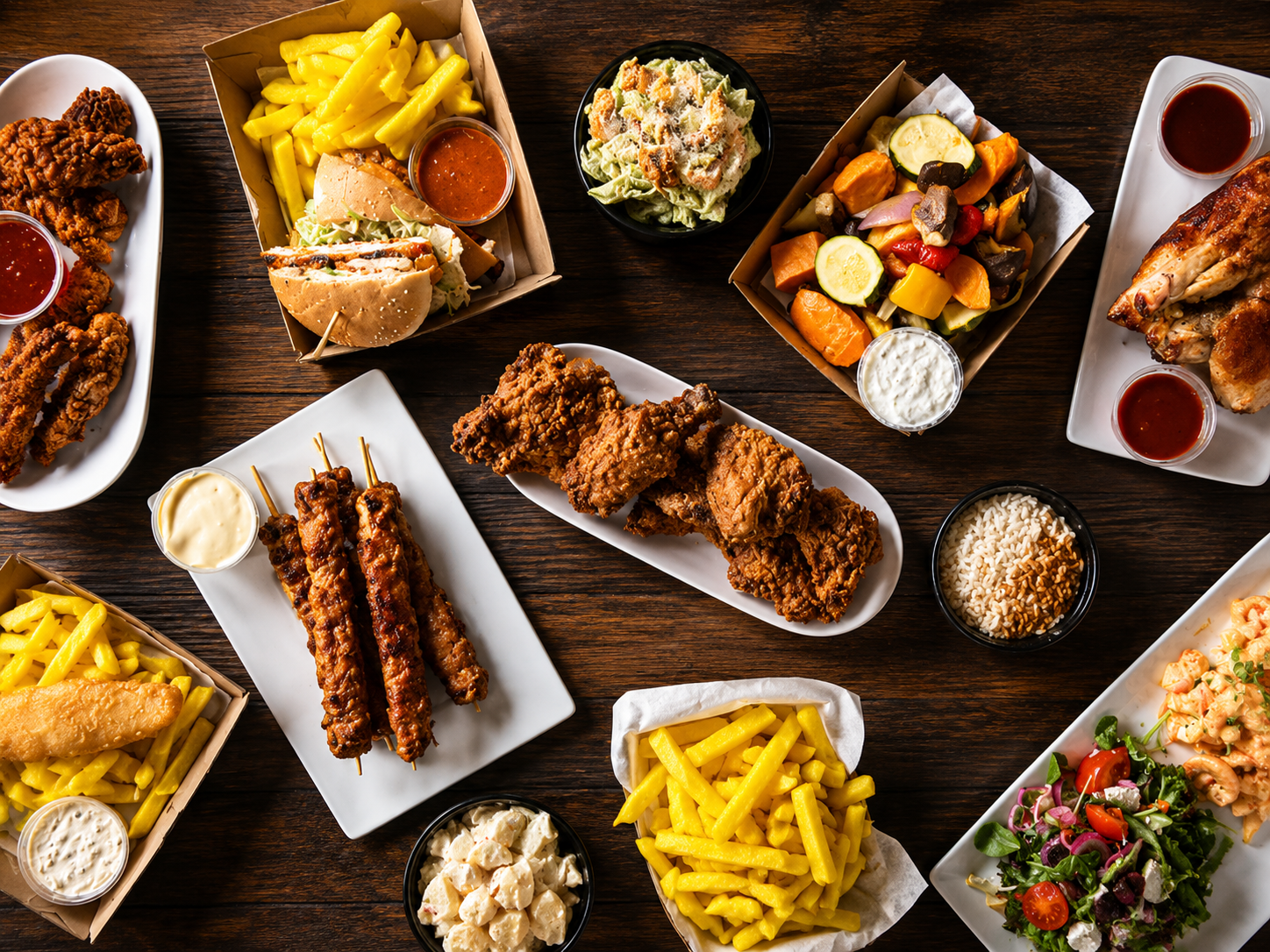Mixed food spread with fried chicken, chips and salads